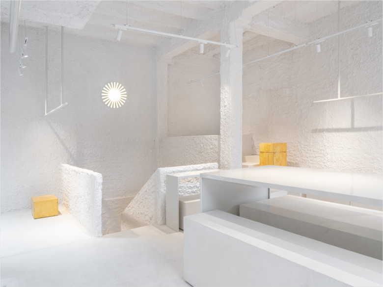 Белый интерьер магазина Стол у лестницы и светильник солнце Thinking MU Store