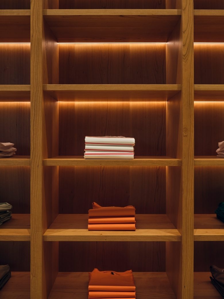 Деревянный стеллаж с аккуратно сложенной одеждой EMKA store