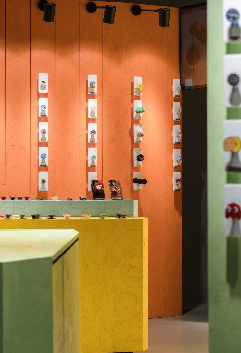 Экспозиция держателей для телефонов на оранжевой стене POPSOCKETS Pop up Store