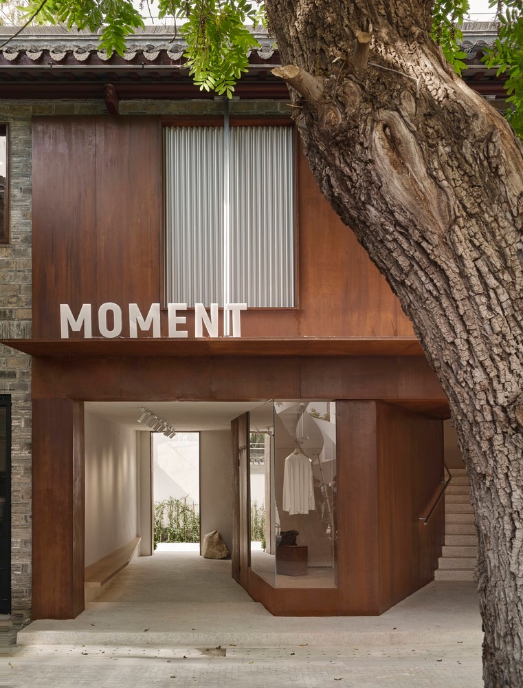 Фасад бутика с деревом на переднем плане Moment Boutique Store