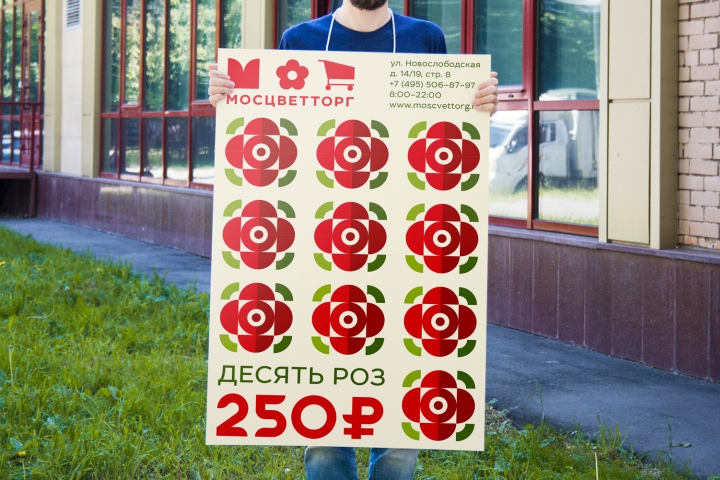 Рекламщик с вывеской о акционном предложении в цветочном магазине Мосцветторг