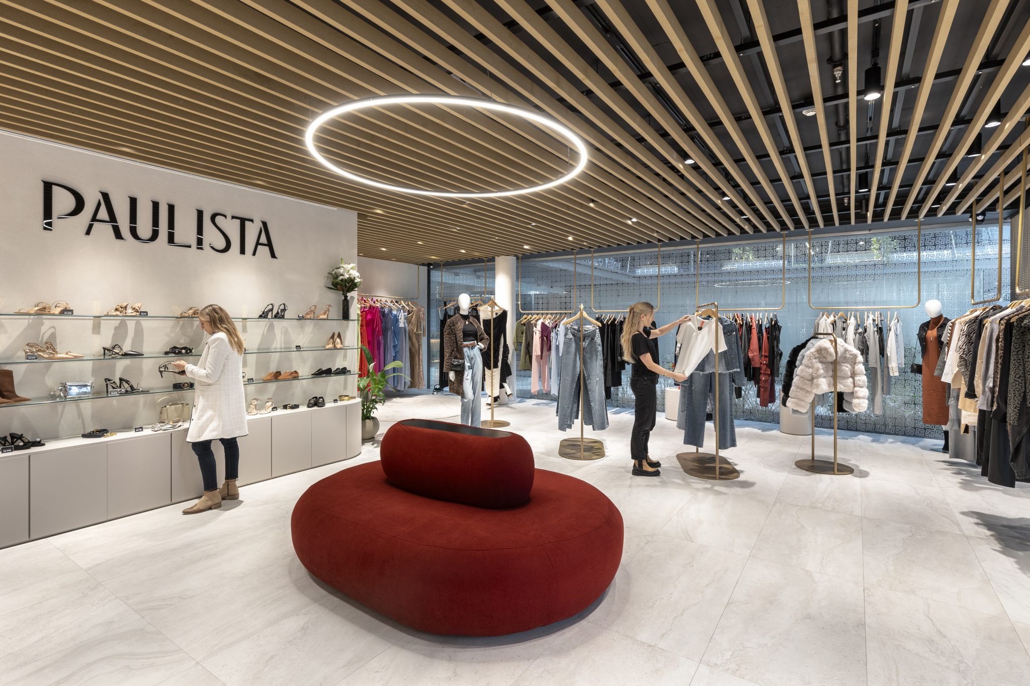 Интерьер магазина одежды с красным диваном и витриной Paulista Store