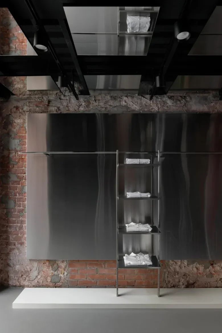 Металлическая стойка с аккуратно сложенной одеждой NUDE STORY store