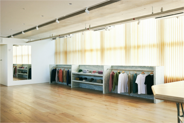 Одежда и аксессуары на стене с каменной отделкой Thisisneverthat store