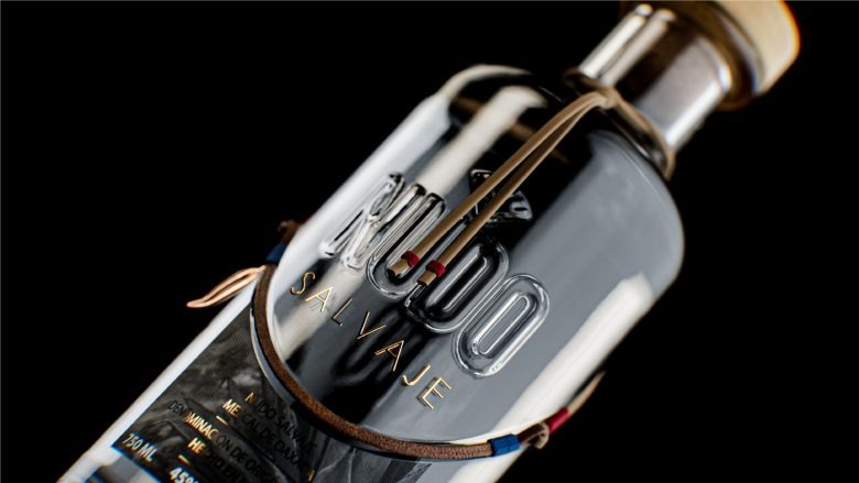 Прозрачная бутылка мескаля с кожаным ремешком крупный план Nudo Salvaje Mezcal