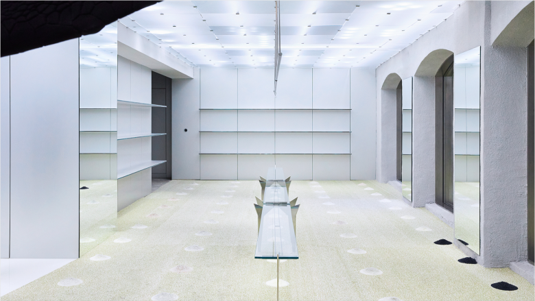 Пустое торговое пространство с белыми стенами и стеклянным столом ADERERROR store