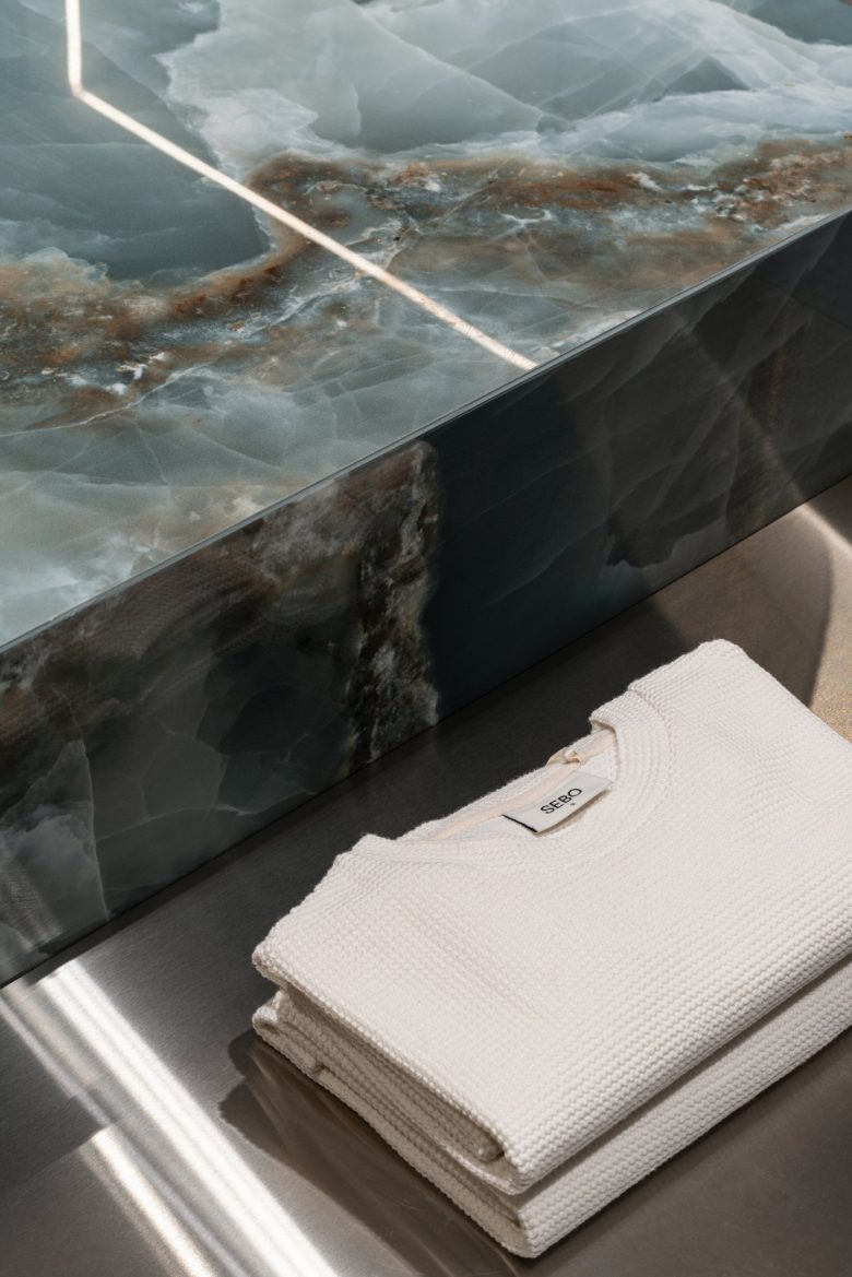 Сложенный белый свитер на металлической поверхности SEBO – Minimalism Meets Technology