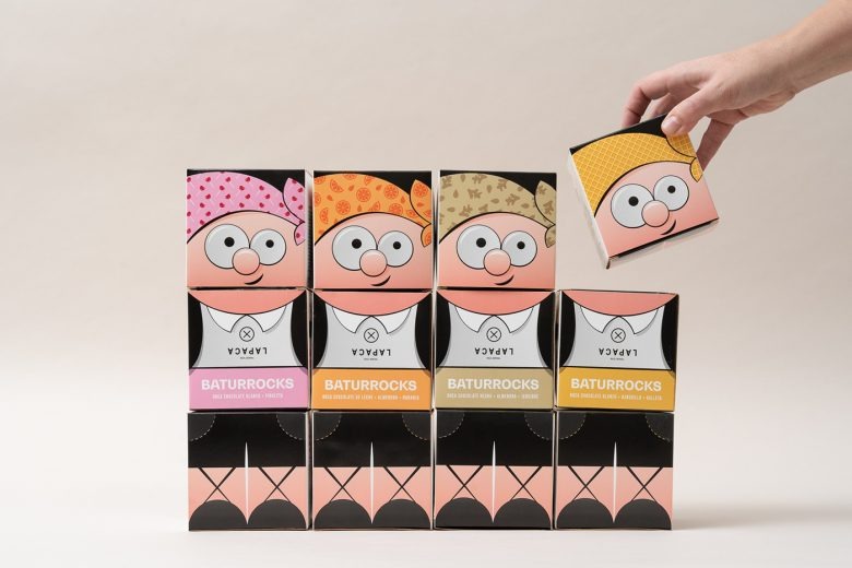 Стопка коробок с персонажами и рукой, берущей упаковку LAPACA Baturrocks