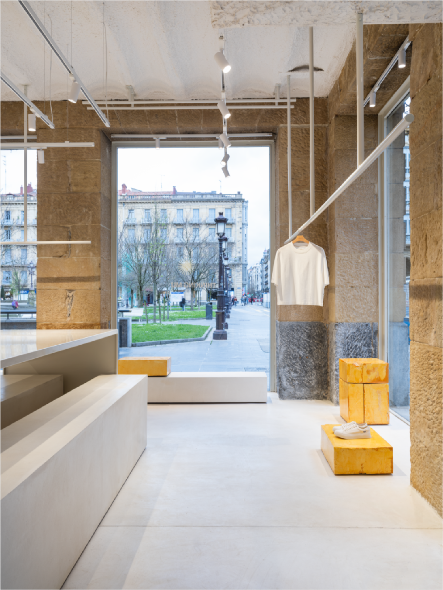 Витрина магазина белая футболка и желтые подиумы Thinking MU Store