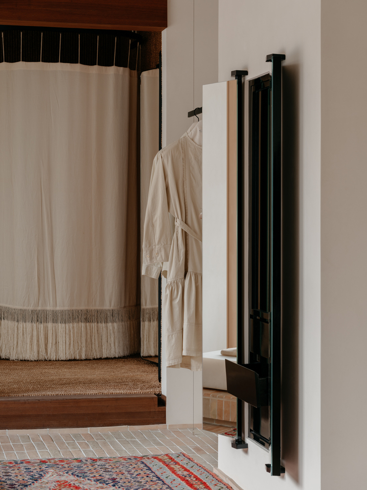 примерочная Lemaire boutique белая штора и вешалки на стене